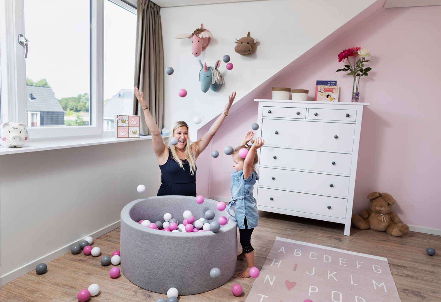 Witte ruime dakkapel kinderkamer, kind spelend met ballenbak.